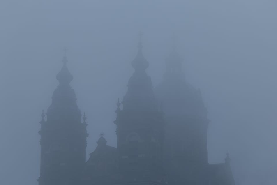 The towers of the Basilica of Saint Nicholas dissolving into thick fog.
