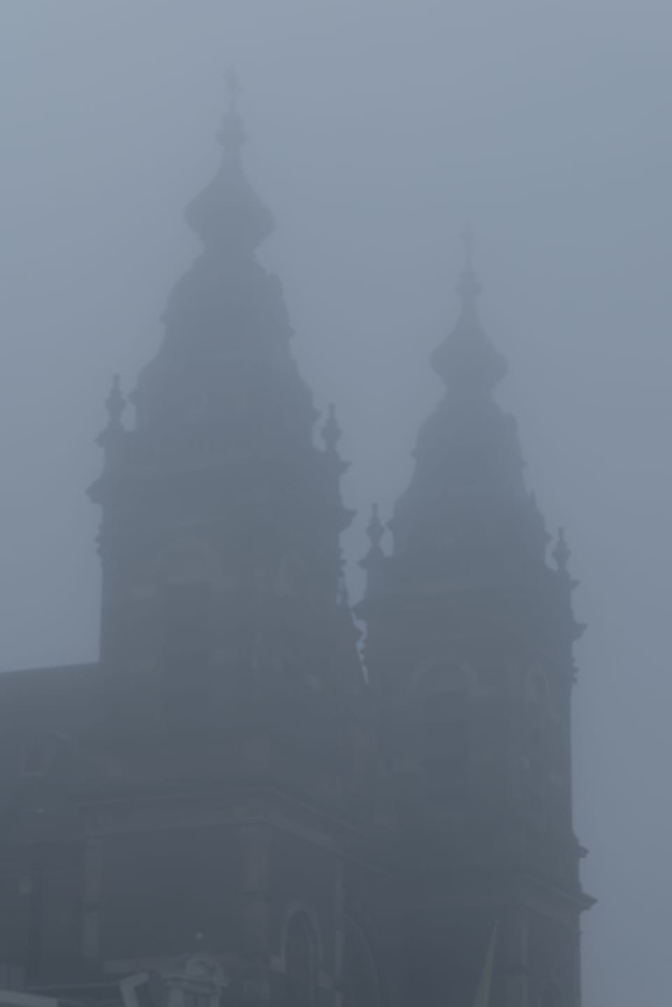 The Basilica of Saint Nicholas looming warm and dim through winter fog.