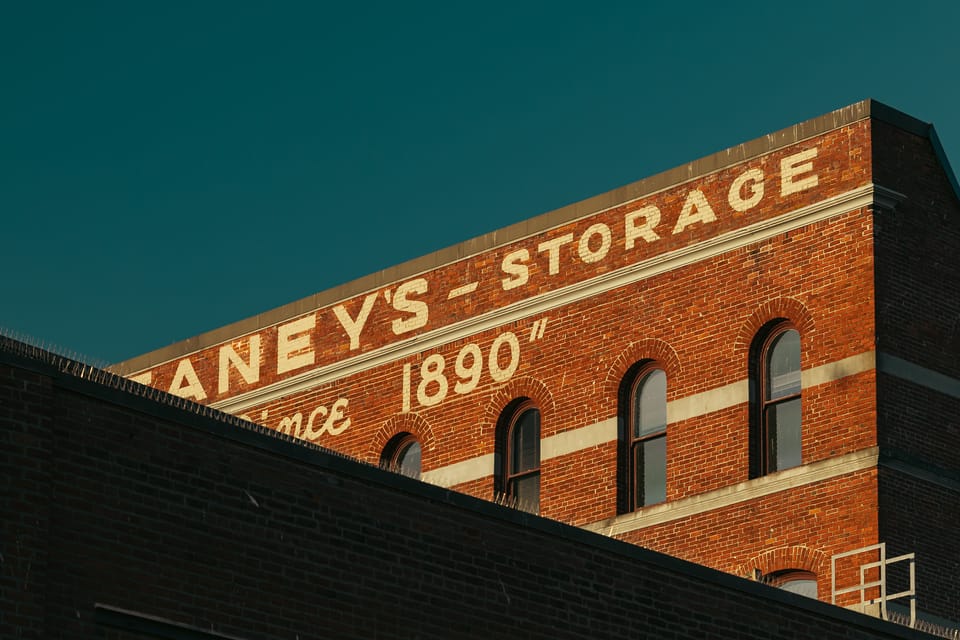 A red brick warehouse facade with painted storage lettering dated 1890.