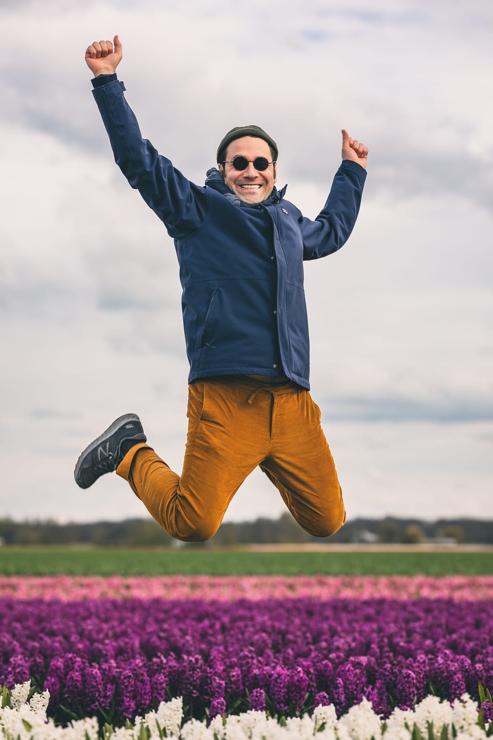 A man leaping with joy above a field of purple and white hyacinths.
