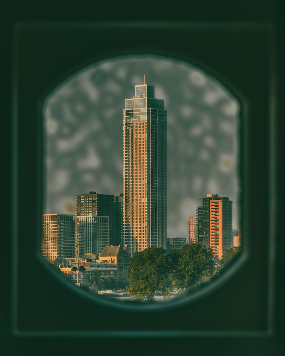 An Amsterdam tower framed inside a green tiled window opening.